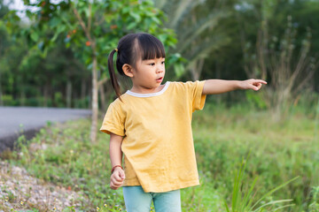 2-3 years old Asian little child girl in the park. She pointing​ her​ finger. At the garden. Spring or summer​ season.