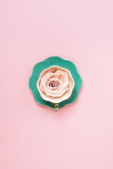 Creative romantic layout gift made of green coffee cup with pink rose on pink background. Minimal floral card. Pastel colors poster. top view. flat lay