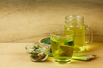 Lemon grass tea in glass and fresh lemon grass sliced and green leaf on wooden background. Healthy herbal drink concept.