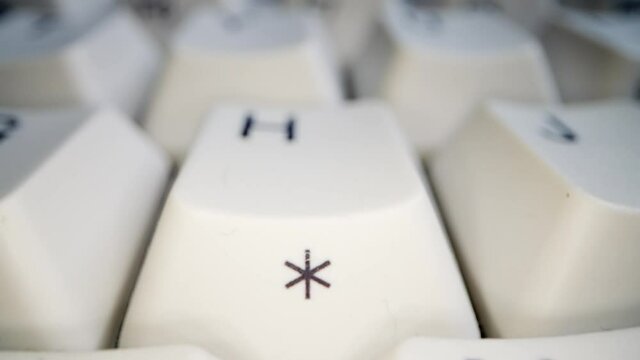 White keyboard asterisk key. Camera movement. Macro photography.