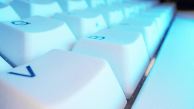 White keyboard keys with Colourful Purple Neon. Macro photography.