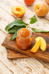 Obraz na płótnie Canvas Jar with tasty peach jam on wooden boards
