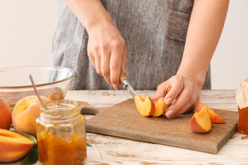 Woman cutting peaches for preparing tasty jam
