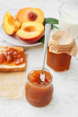 Jar with tasty peach jam on table