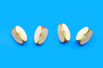 Ripe apple slices on blue background.