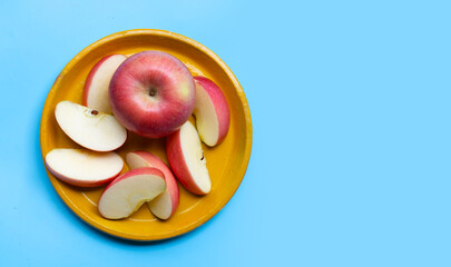 Ripe apple on plate on blue background.