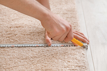 Man with measuring tape cutting carpet