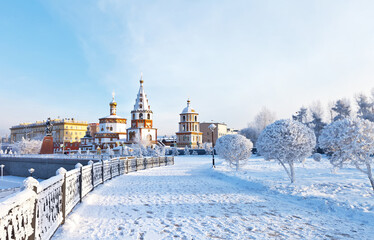 Siberia. Irkutsk. View from the snow-covered lower embankment of the Angara River to the Epiphany Cathedral and the monument to the founders of the city on a cold day. Beautiful winter cityscape