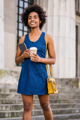 Business woman holding digital tablet and coffee outdoors.