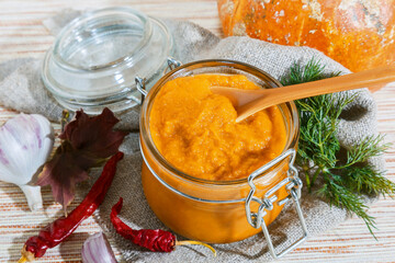 Mashed pumpkin in a glass jar, homemade healthy natural autumn food vegetable pumpkin vegetarian caviar soup canned with chili pepper, recipe traditional russian dish