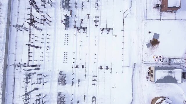Electric station poles in winter. Action. Top view of modern electrical substation with rows of transformers in winter. Rows of electric poles at station