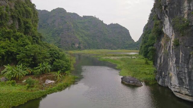 Aerial shot of beautiful limestone mountains with passes carved by a river in Ninh Binh region, a famous tourist destination in northern Vietnam. Travel to Vietnam concept