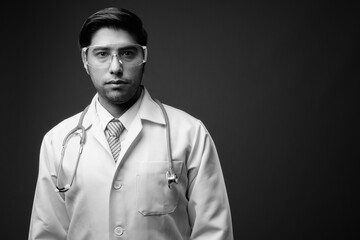 Young handsome Iranian man doctor wearing protective glasses