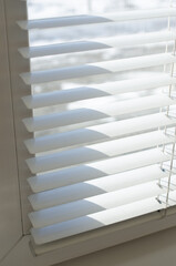 Obraz premium White blinds close up against the light from the window