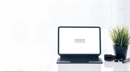 Mockup blank screen tablet with magic keyboard on white table and white background.