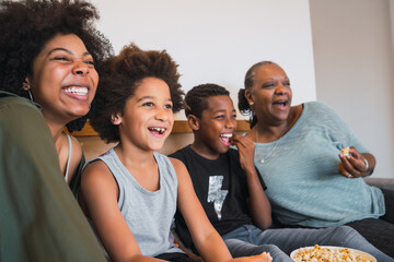 Grandmother, mother and children watching a movie at home.