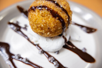 Fried ice cream with cream, chocolate syrup and chips on plate