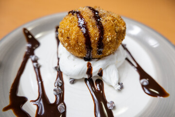 Fried ice cream with chocolate syrup and cream on plate