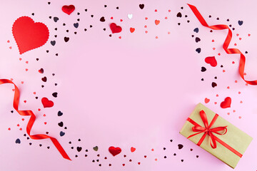 Valentine’s Day background. Gift, red ribbons, decorative hearts, confetti on a pink background. The Concept Of Valentines Day. Greeting banner or postcard. Flat lay, top view, copy space