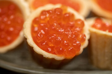 Tartlets with salmon caviar on a platter. Close-up, selective focus.