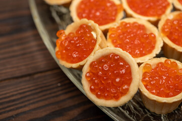 Tartlets with salmon caviar on a platter. Close-up, selective focus.
