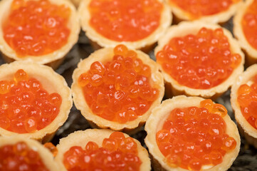 Tartlets with salmon caviar on a platter. Close-up, selective focus.