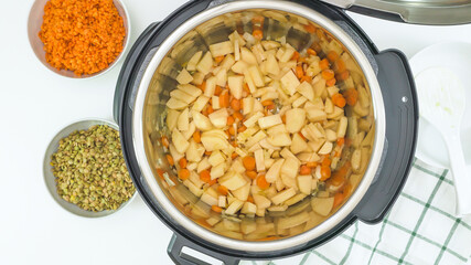 Multi cooker recipe. Cooking vegetables. Carrot, potatoes, lentils and some ingredients close up in a pot, view from above