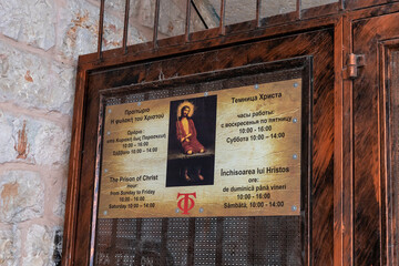 The sign with opening hours on the door of the Prison of Christ in the Greek Orthodox monastery on Via Dolorosa Street in the old city of Jerusalem in Israel