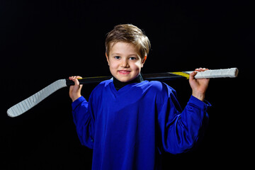 boy hockey player with a stick in a blue uniform on a black background