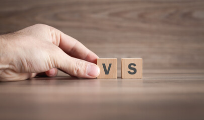 Male hand showing VS word on wooden cube.