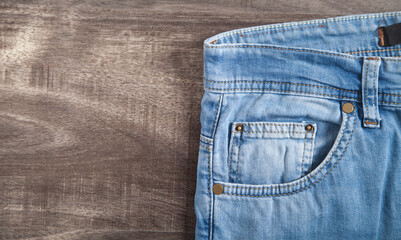 Jeans on the brown wooden background.