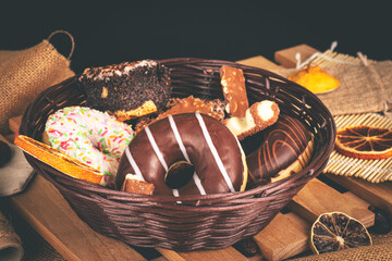 A basket of sweets on a background of dried fruit and jute. Donuts, chocolate, and a bar © Exploder