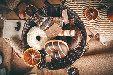A basket of sweets on a background of dried fruit and jute. Donuts, chocolate, and a bar - obrazy, fototapety, plakaty