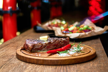 Master chef cooking barbecue Beef Grilled steak meat with fire flames on wooden table