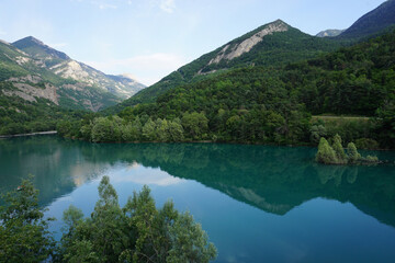 Fototapeta premium mirror reflection of the mountains and clouds in Serre Ponçon lake, France with a small island