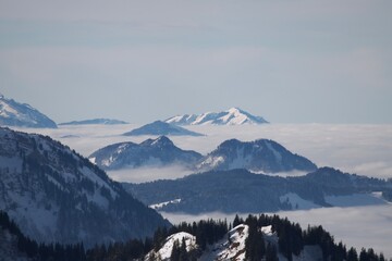 Winterlandschaft der schneebedeckten  bayerischen Alpen über Wolken vor blauem Himmel