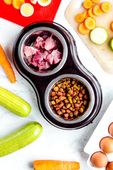 Dogfood, eggs, meat, carrot and courgette on table background top view