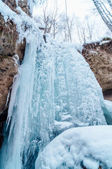 A frozen small waterfall covered with snow. Waterfall in winter.