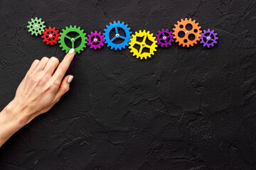 Teamwork concept. Hand connecting gears into puzzle - symbol of working mechanism