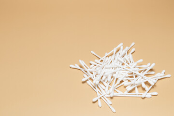 White plastic cotton swabs on a brown background with blank copy space.