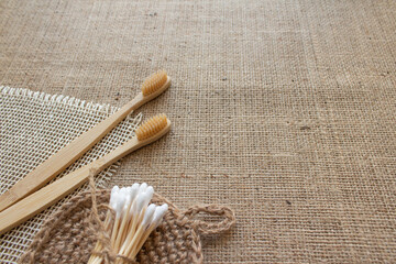 Natural bathroom tools, sustainable zero waste and lifestyle concept. Wooden toothbrushes, bamboo swabs, and handmade jute body washclothes on fabric background with copy space. Mockup