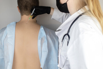 An orthopedic surgeon gives an injection in the cervical vertebrae. Treatment of osteoarthritis...