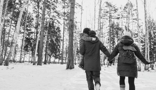 Family walking in winter forest. Black and white toned photo