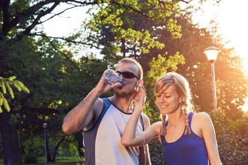 Fototapeta premium Two young sporty man and woman exercising in park at summertime season.