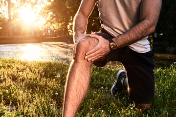 Sports jogging running injury in the park, young man having knee pain problem.