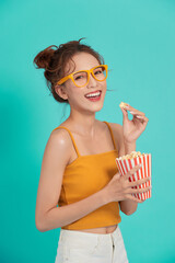 Excited young Asian woman eating popcorn isolated on blue background.