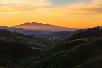 Obraz premium Sunset in the mountains. A view from the hills around Raglan, New Zealand, looking towards Mount Karioi