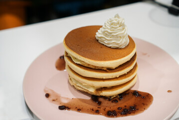 A stacks of Japanese fluffy pancake topped with whipped fresh cream and red bean Azuki.