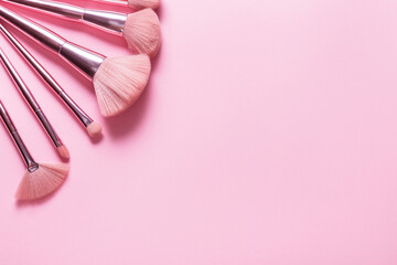 Set of different cosmetic brushed on pink background, copy space