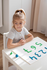 Little girl make a numbers from plasticine. home education, motor skills practice.